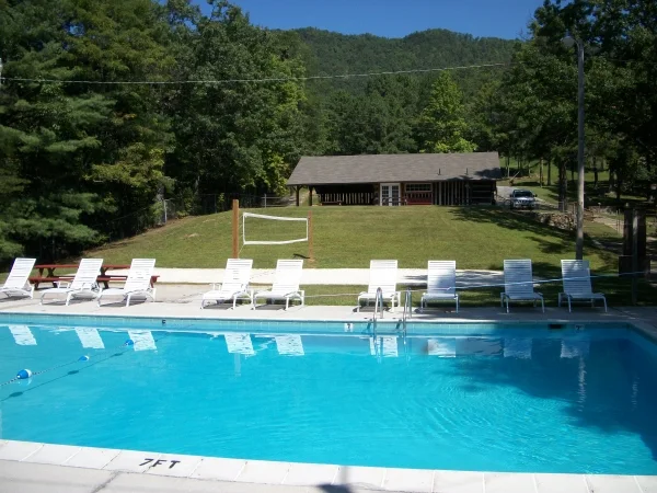 Outdoor swimming pool with lounge chairs and wooded mountain views