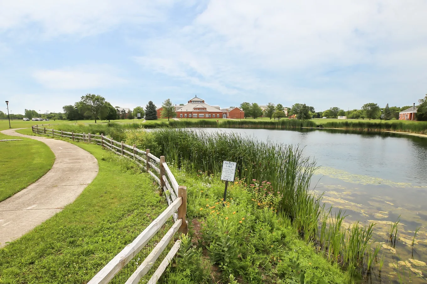 Walking path beside a pond on the landscaped facility grounds