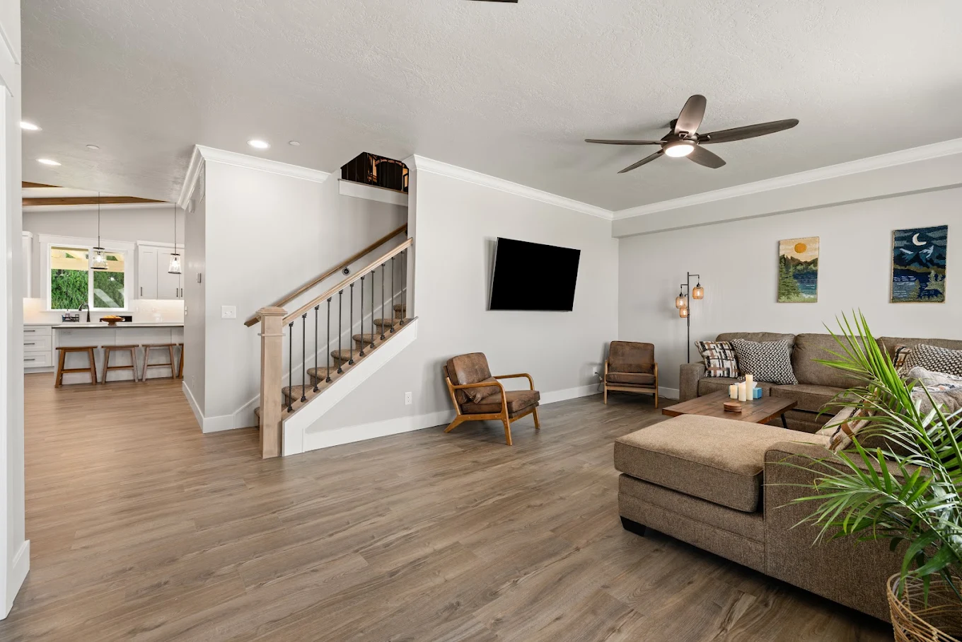 Living area with sectional sofa, chairs, TV, and staircase
