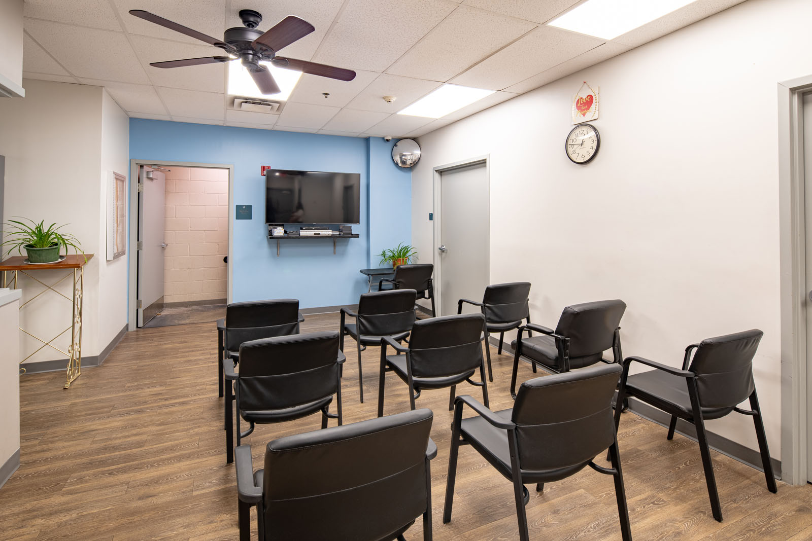 Group therapy room with chairs, TV, and ceiling fan