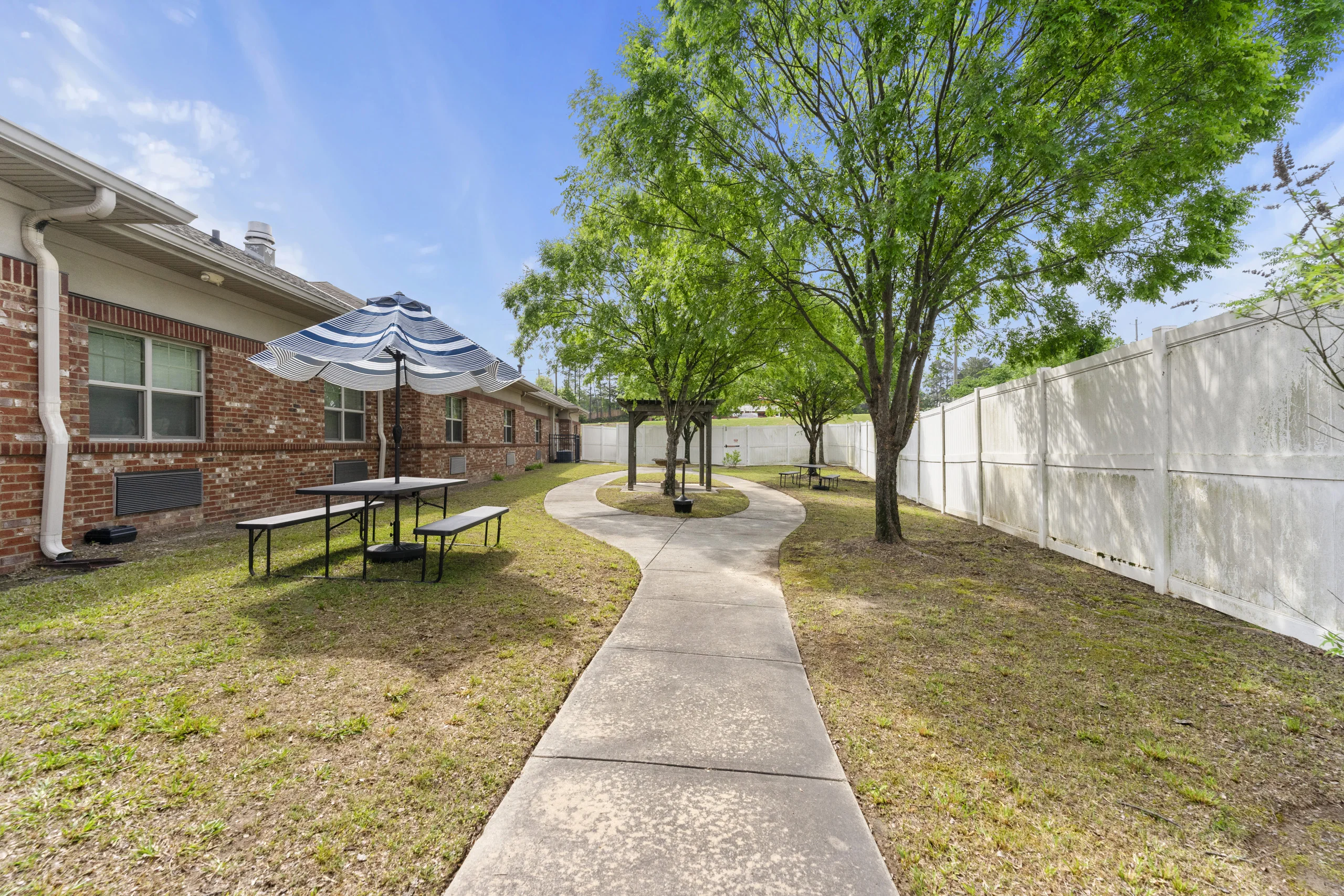 Landscaped outdoor walking path with shaded seating and picnic area inside the facility courtyard
