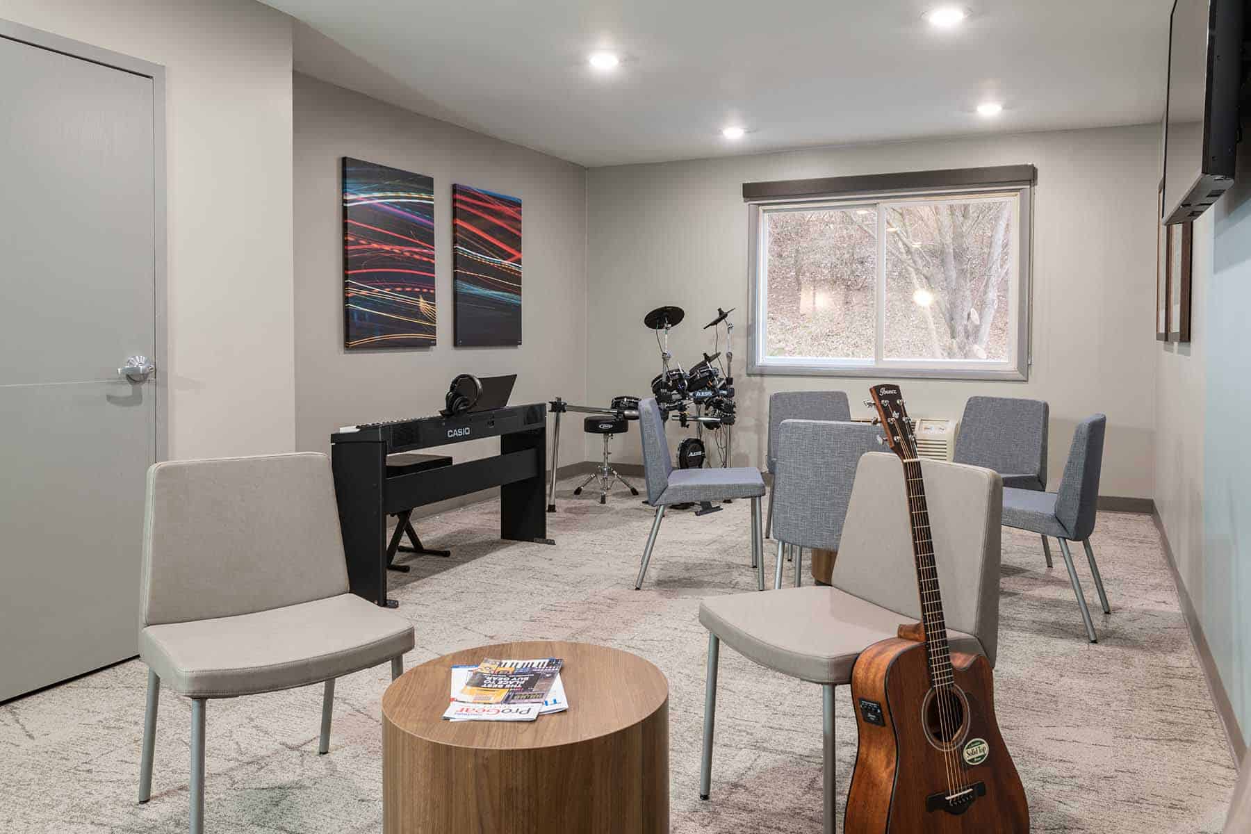 A music therapy room with chairs, a keyboard, and a drum set.