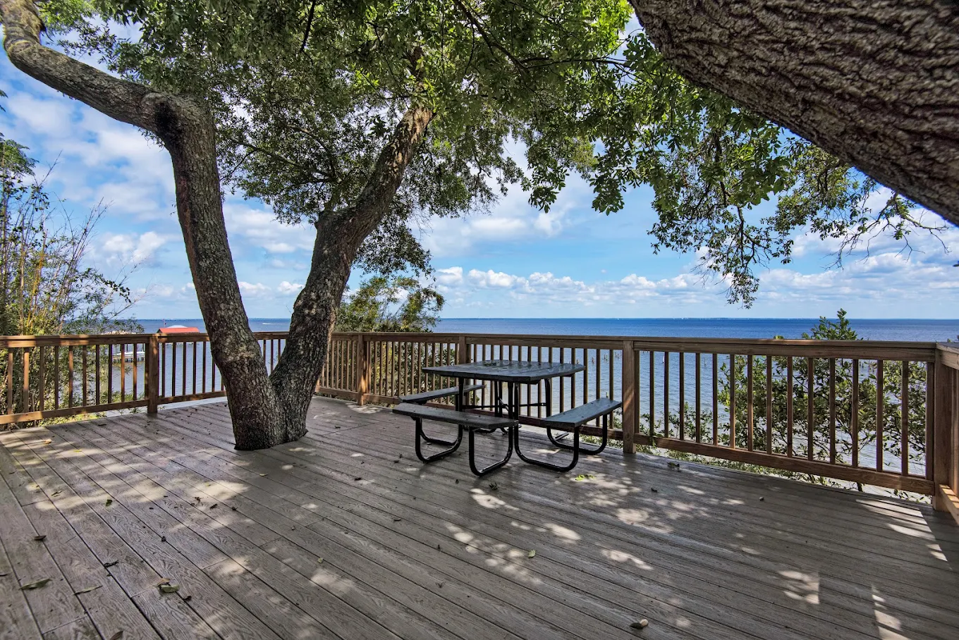 Shaded wooden deck with picnic table overlooking the water