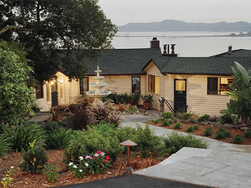 Landscaped courtyard with fountain and view of water beyond buildings