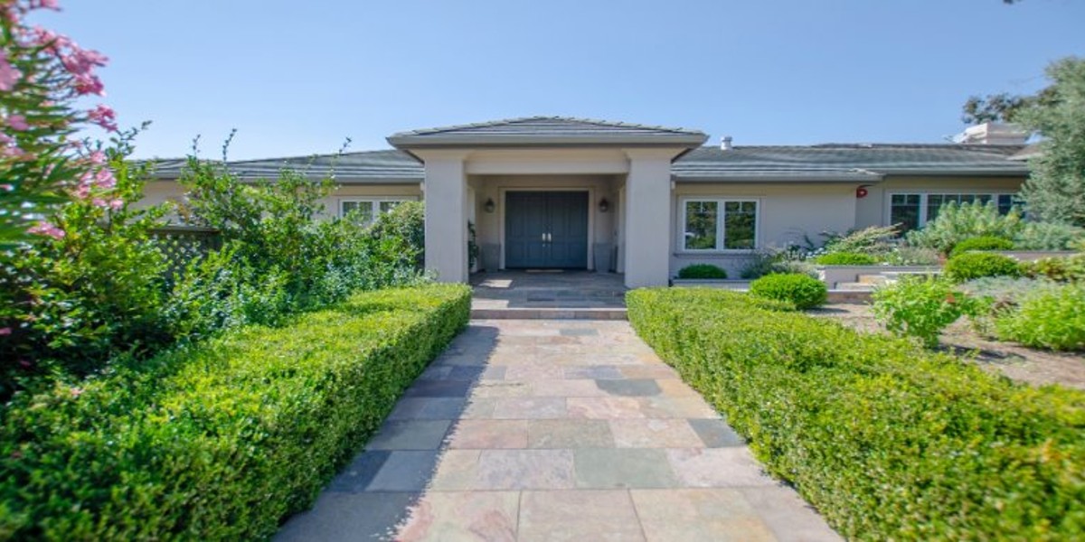 Front exterior view with landscaped greenery and entryway.