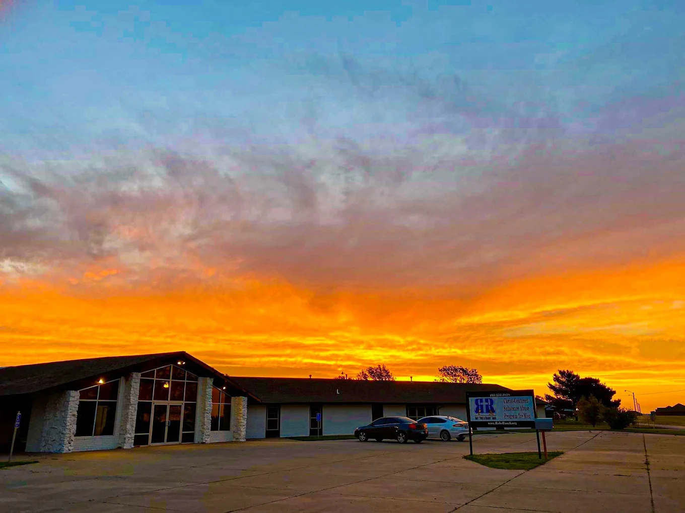 Facility exterior at sunset with main entrance and parking area