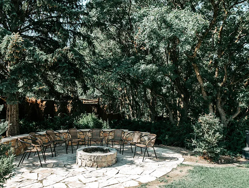 Outdoor fire pit with chairs surrounded by trees