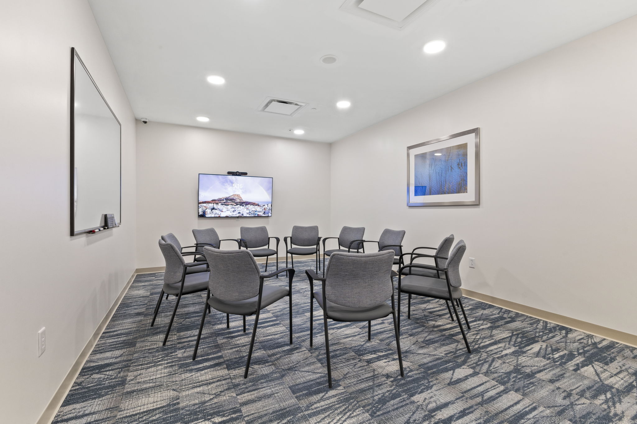 A group therapy room with chairs arranged in a circle and a TV screen.