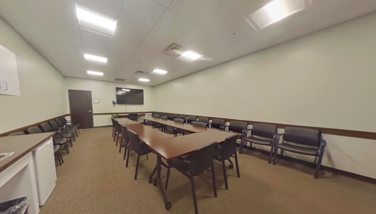 Large meeting room with tables, chairs, and TV