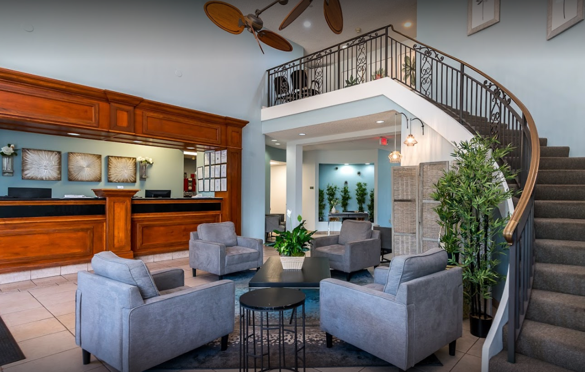 Lobby with gray chairs and a wooden reception desk.