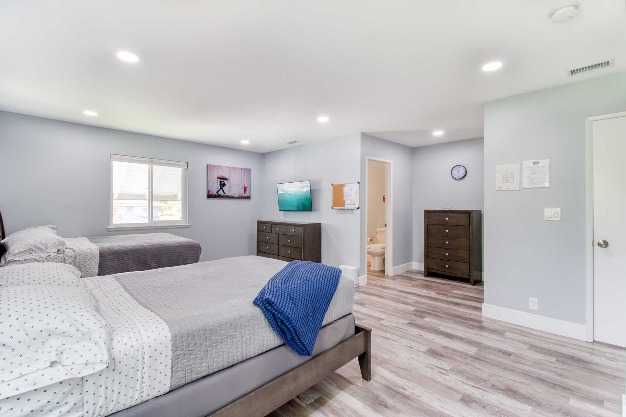Large shared bedroom with gray tones and natural lighting