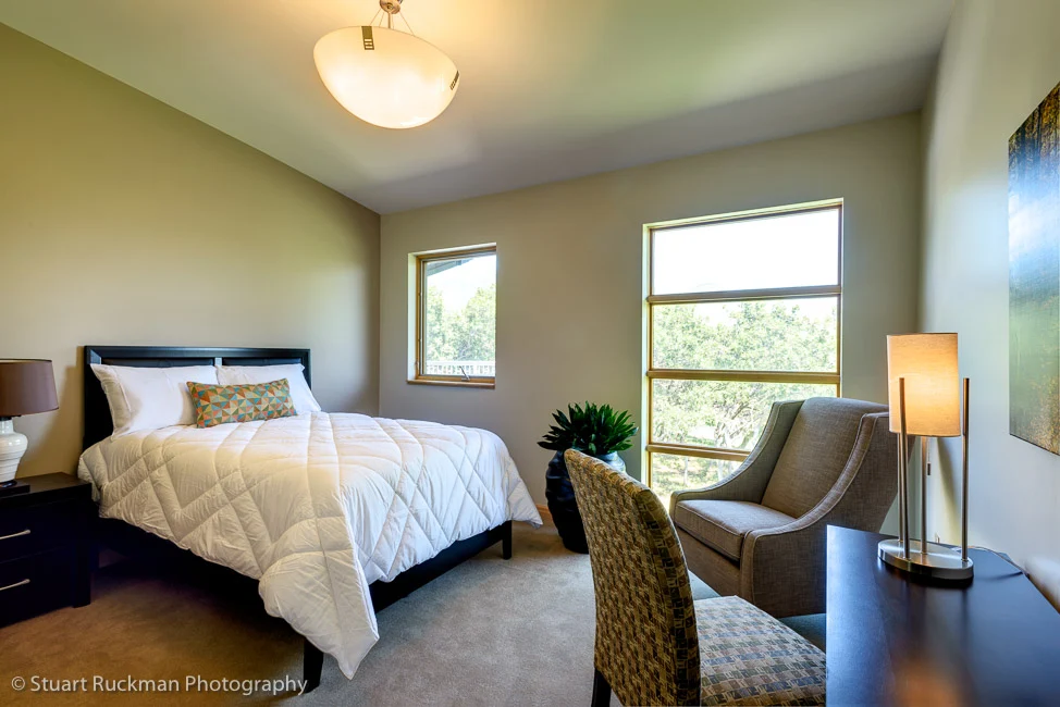 Private bedroom with bed, chairs, and natural light.