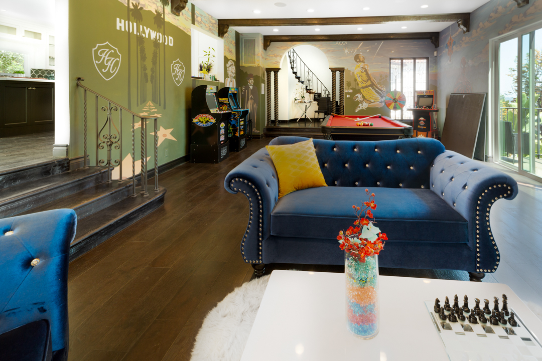 Lounge area with blue tufted couch and arcade games