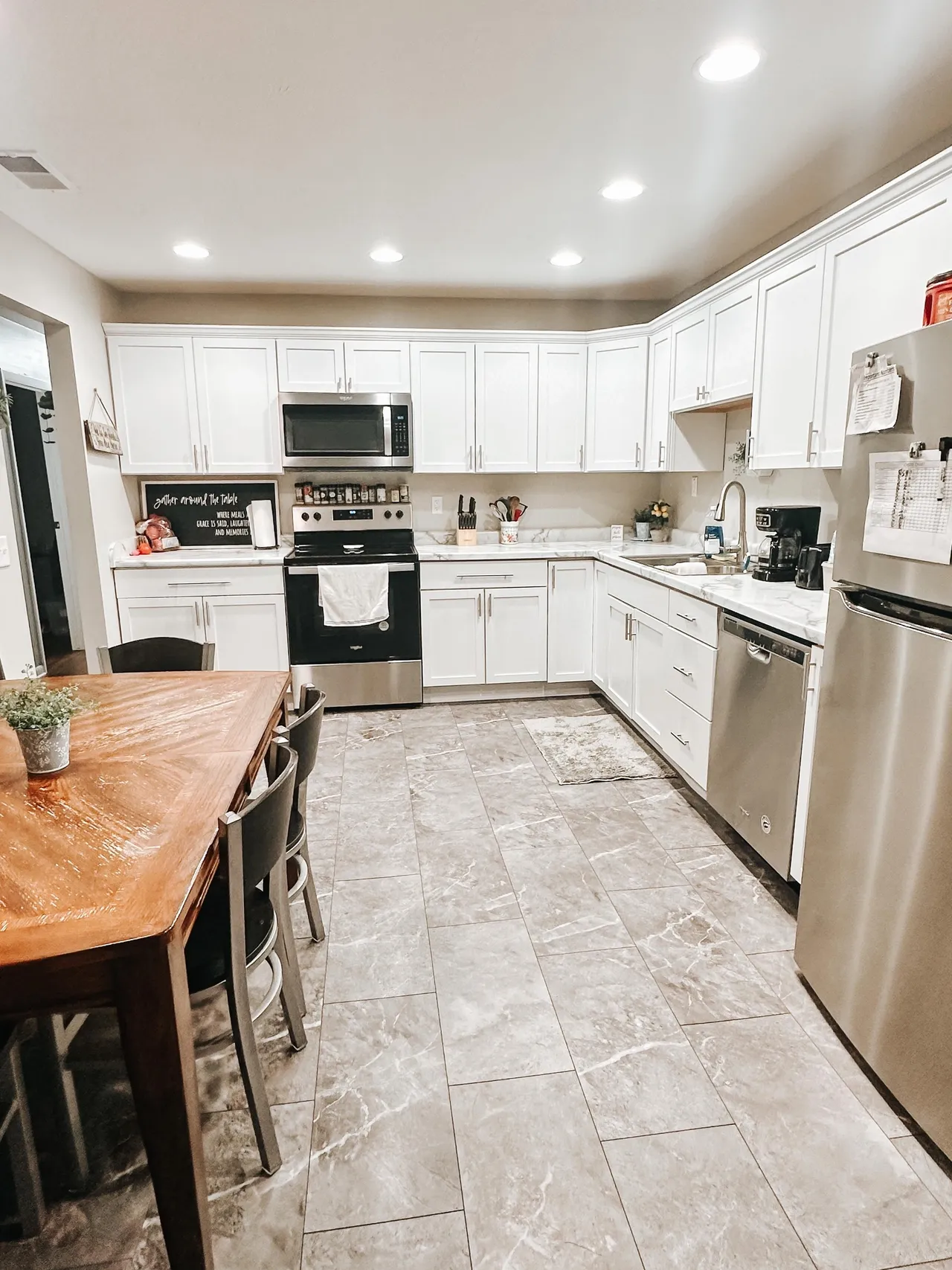 Bright kitchen with white cabinets, stainless steel appliances, and dining table