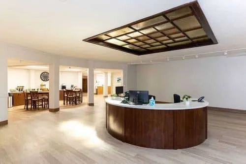 Curved wooden reception desk under a large skylight