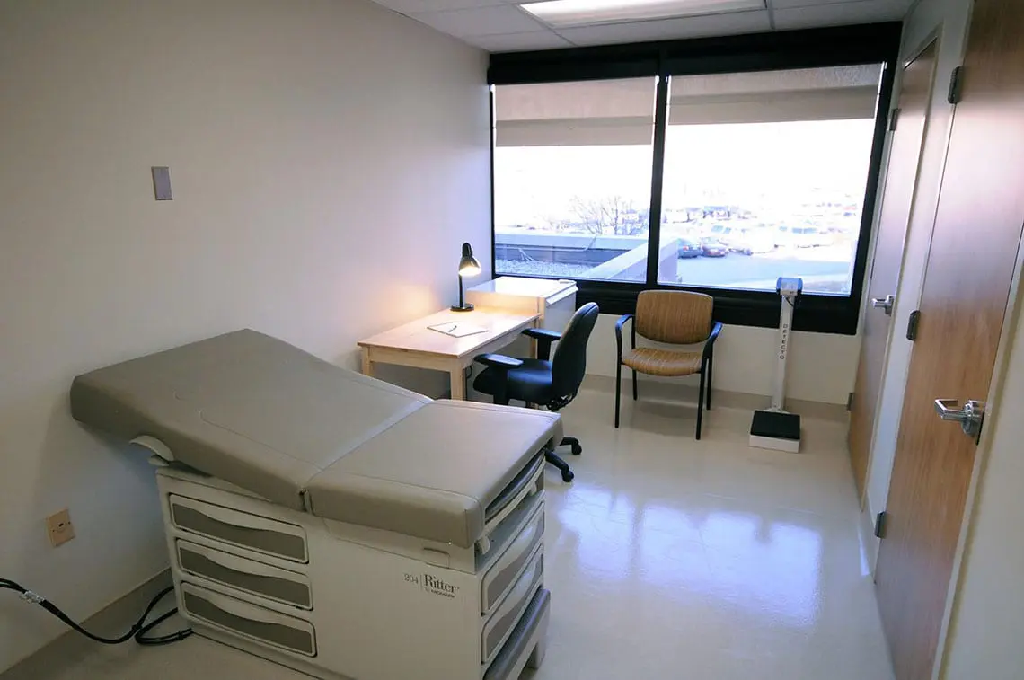 Exam room with exam table, desk, and large window