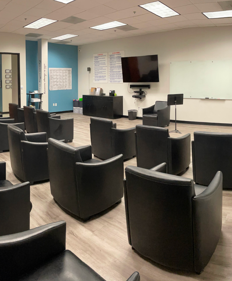 Circle of black chairs in modern group therapy meeting room