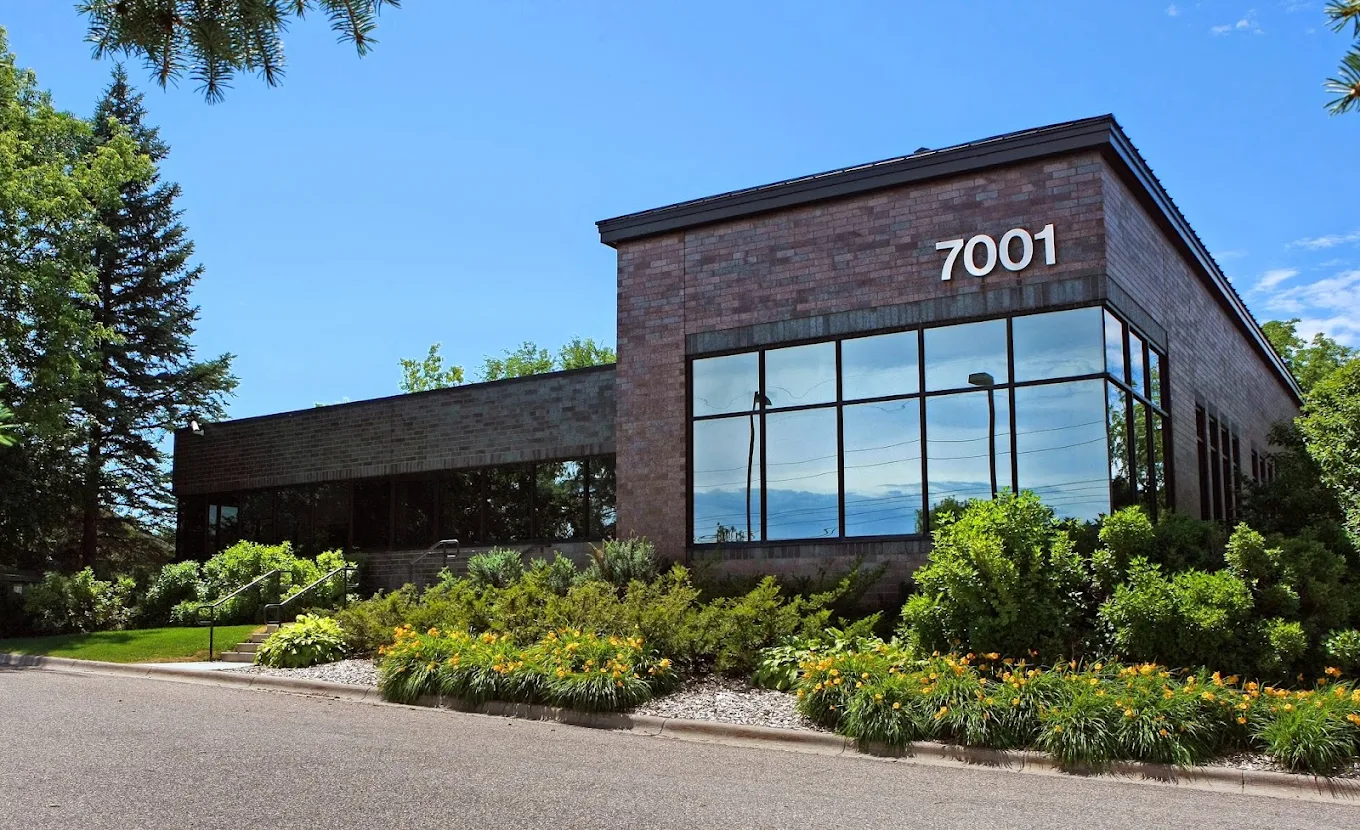 Brick facility exterior with large windows and landscaping