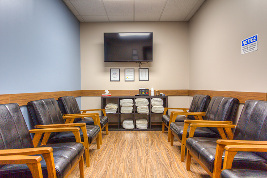 BrightView Ashtabula group room with rows of cushioned chairs, television, shelving, and wood-look flooring