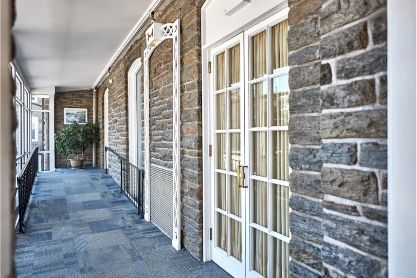 Covered stone walkway with windows and guest room entrances.