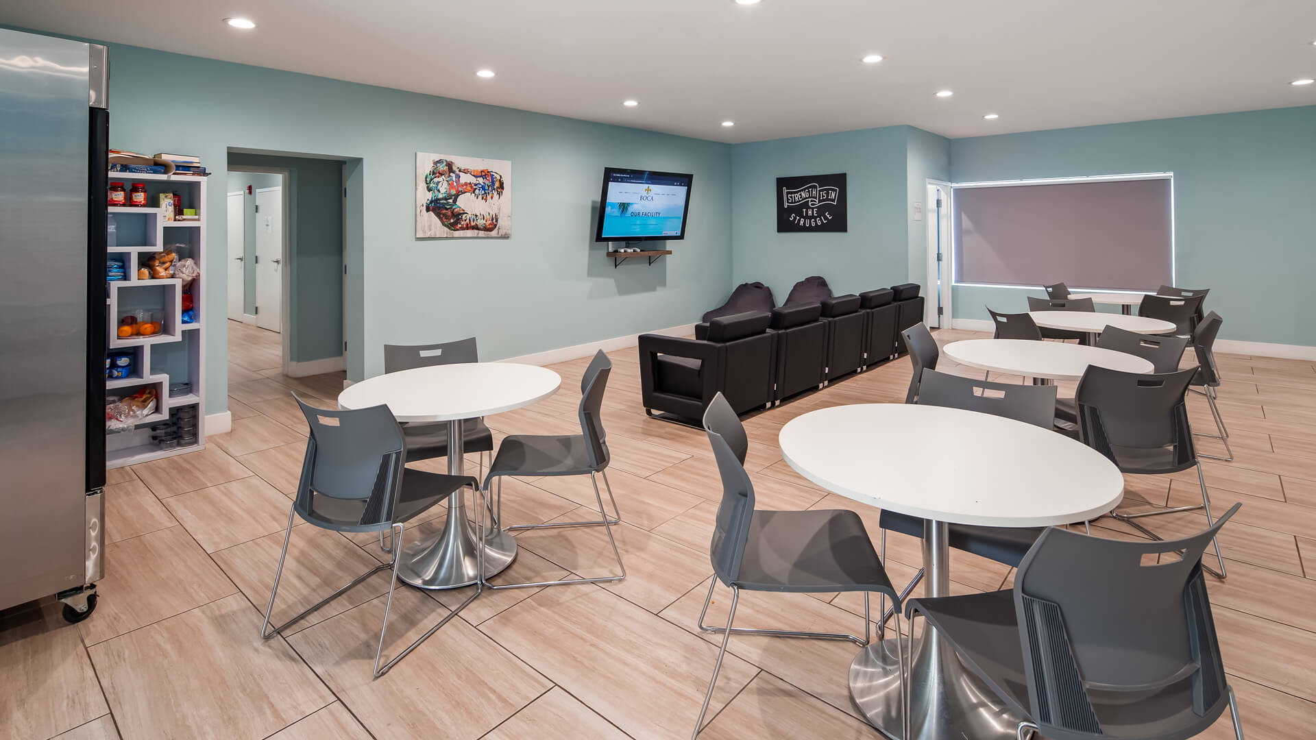 Lounge area with tables, seating, snacks, and a large TV.