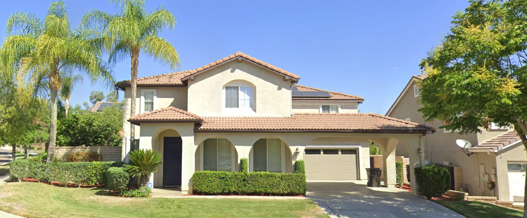 Two-story beige home with palm trees and front driveway