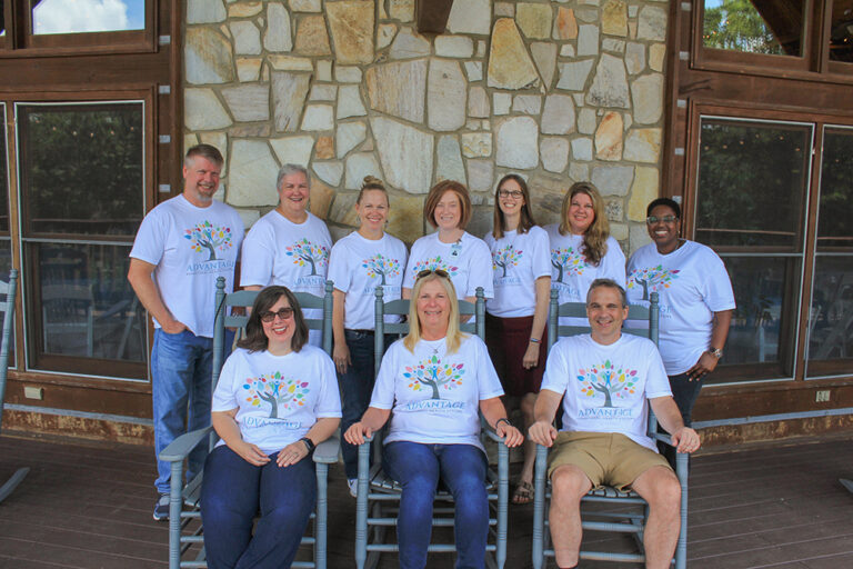 Team of staff smiling in matching shirts outside facility