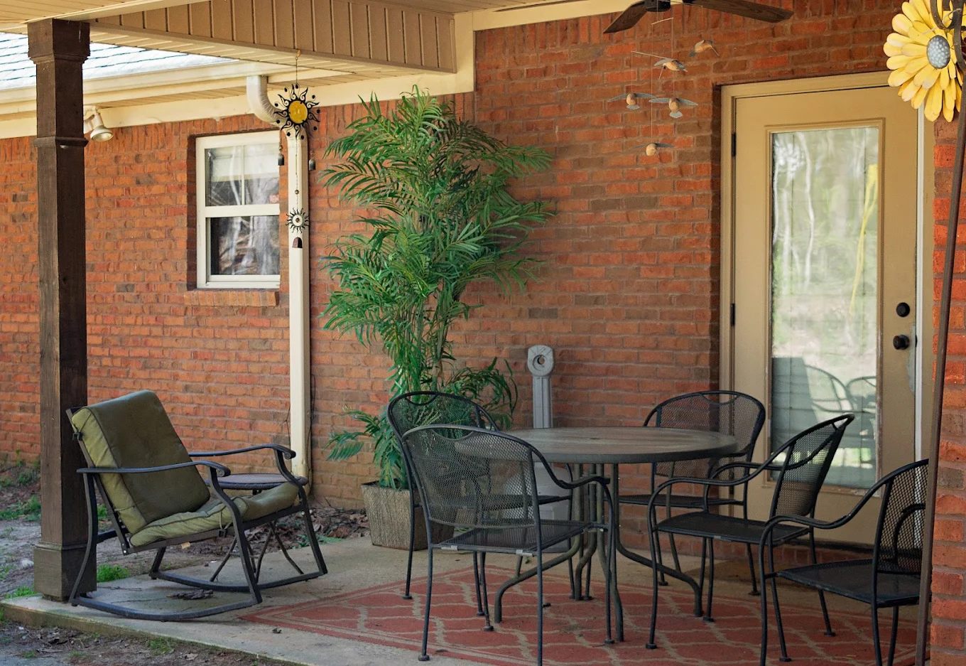 Covered brick patio with table, chairs, and outdoor seating