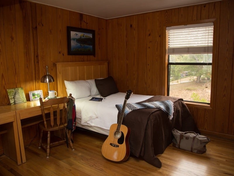 Cozy wooden room with bed, desk, and window view