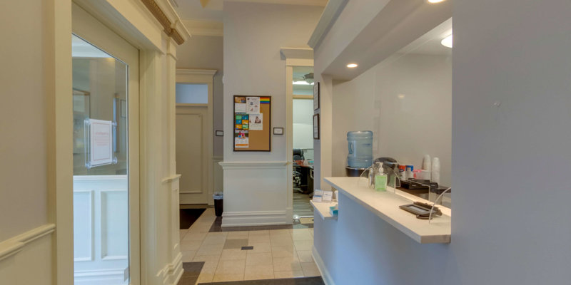 A bright, welcoming hallway leads to a reception area with a water cooler, soft lighting, and a clean, modern design, creating a calm atmosphere.