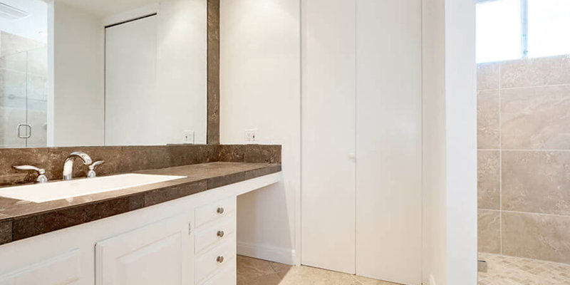  A modern, elegant bathroom featuring a spacious countertop, large mirror, bright lighting, and a sleek glass-enclosed shower with neutral tile.