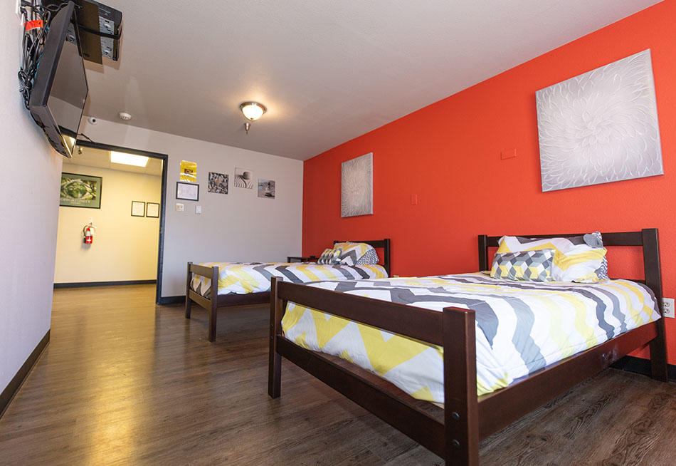 Two twin beds with bright bedding and orange accent wall