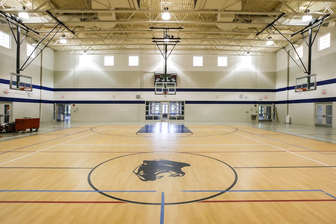 Indoor gymnasium with basketball court, hoops, and high ceiling