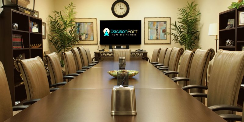 A professional and welcoming conference room with comfortable chairs, modern decor, and a screen displaying a hopeful message.