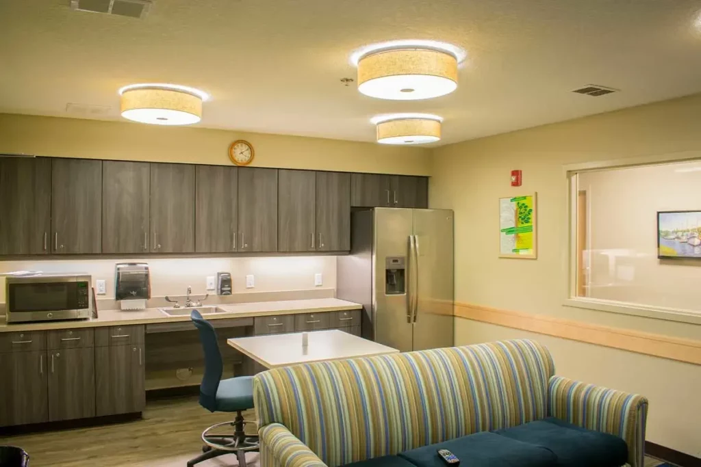 Modern kitchen with gray cabinets, stainless fridge, and seating area