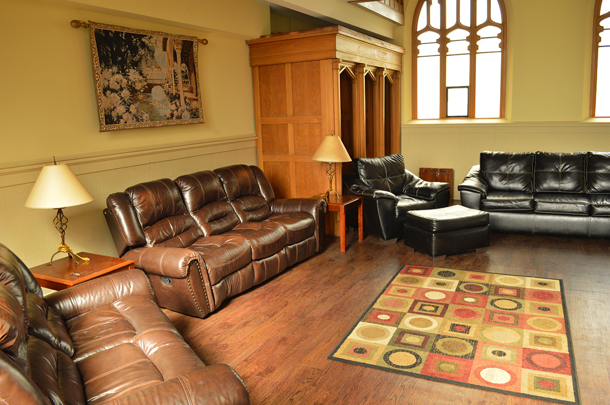 Lounge with brown leather couches, armchairs, lamps, and a patterned rug