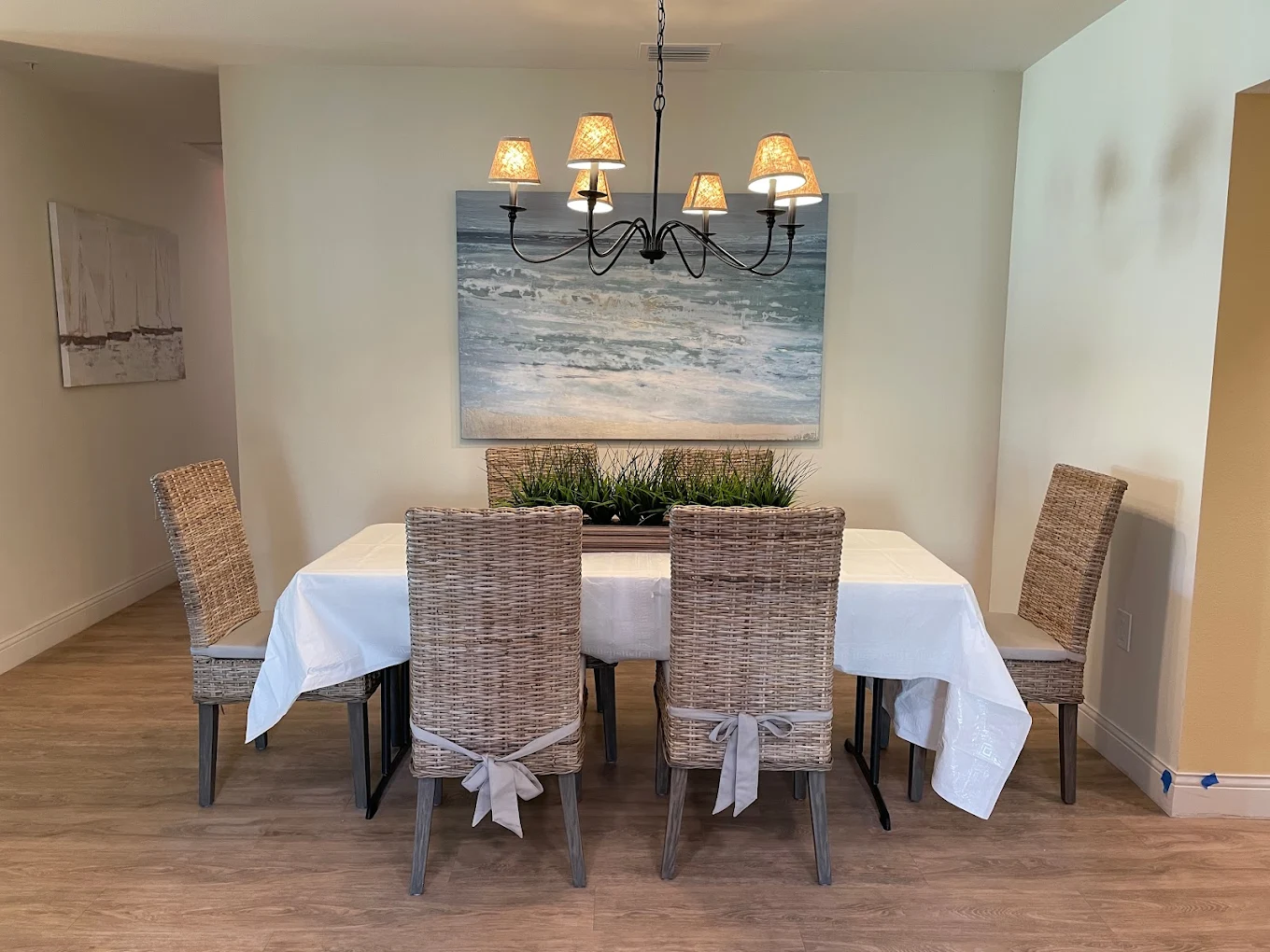 Dining table with wicker chairs and beach artwork