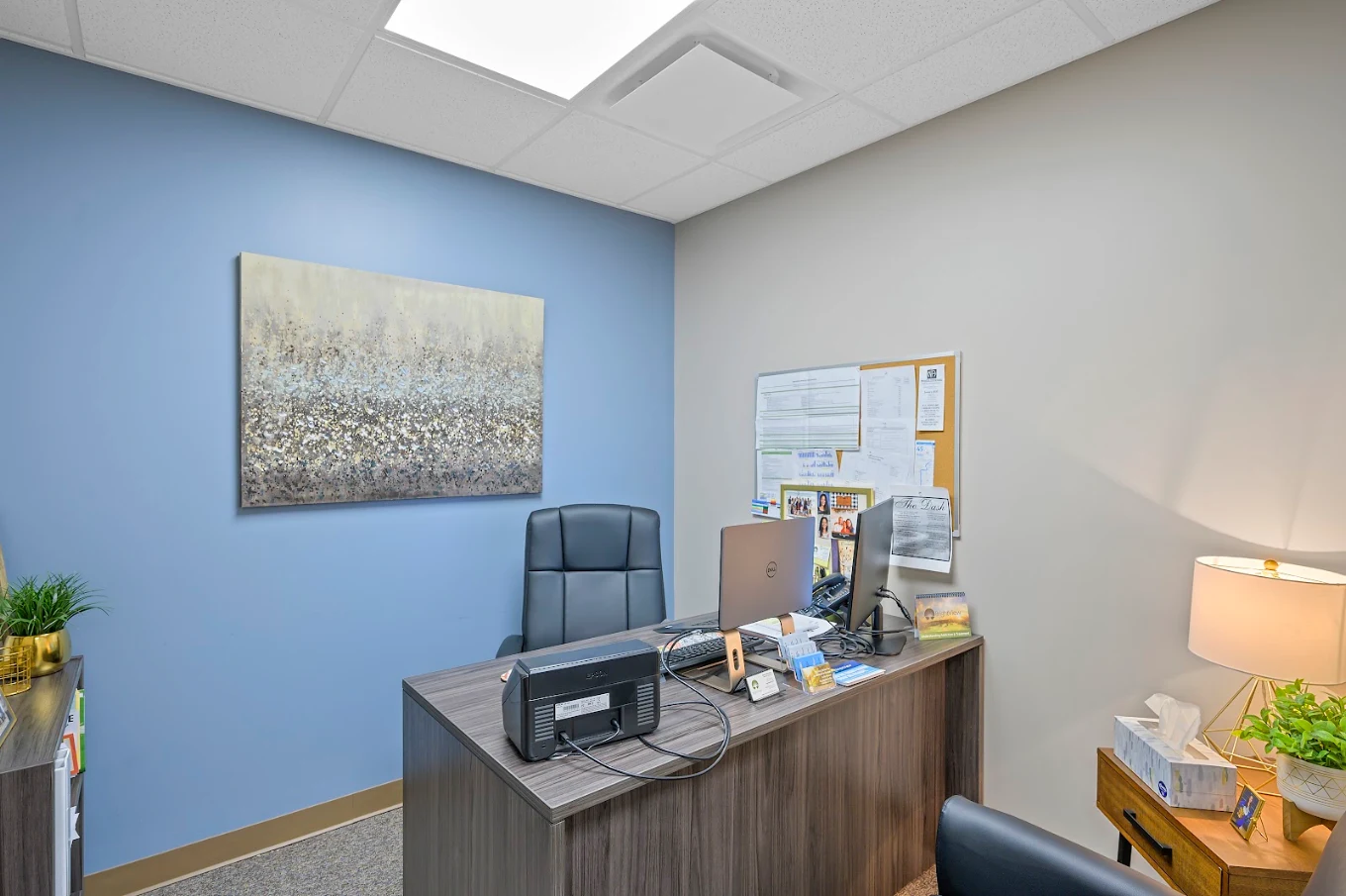 Private consultation room with desk, computers, and blue accent wall