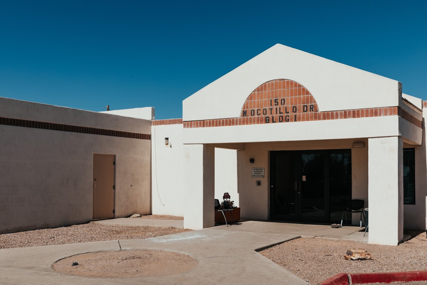 A beige stucco building with a brown arched entrance and glass doors.