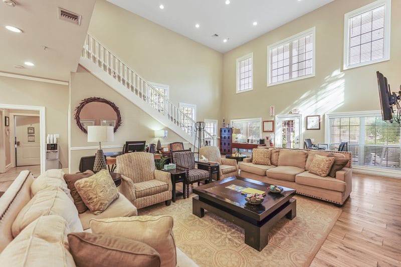 Cozy living room with sofas, armchairs, coffee tables, and stairway in a spacious two-story room