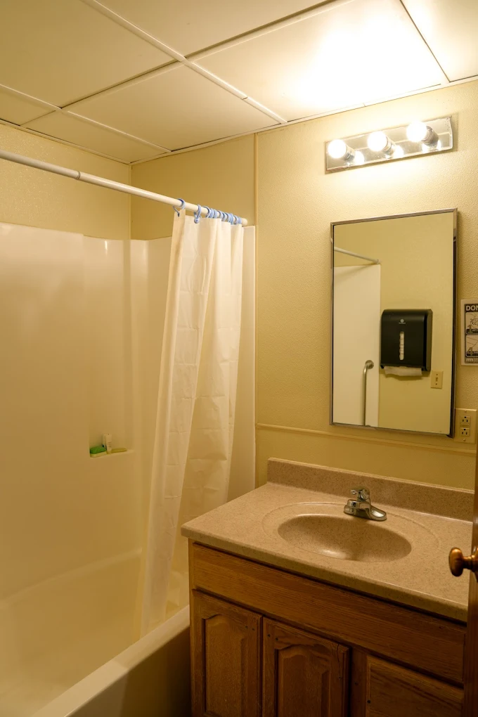 Clean shared bathroom with shower, sink, and mirror