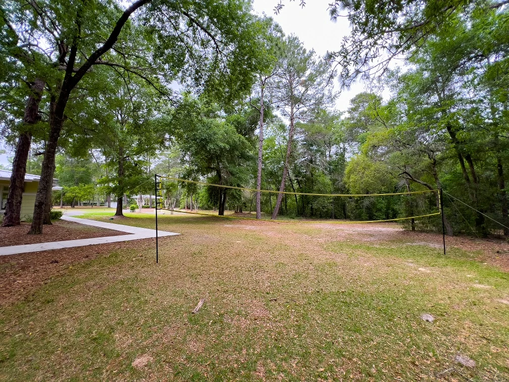 Grass volleyball court located on wooded recovery center grounds with walking path nearby