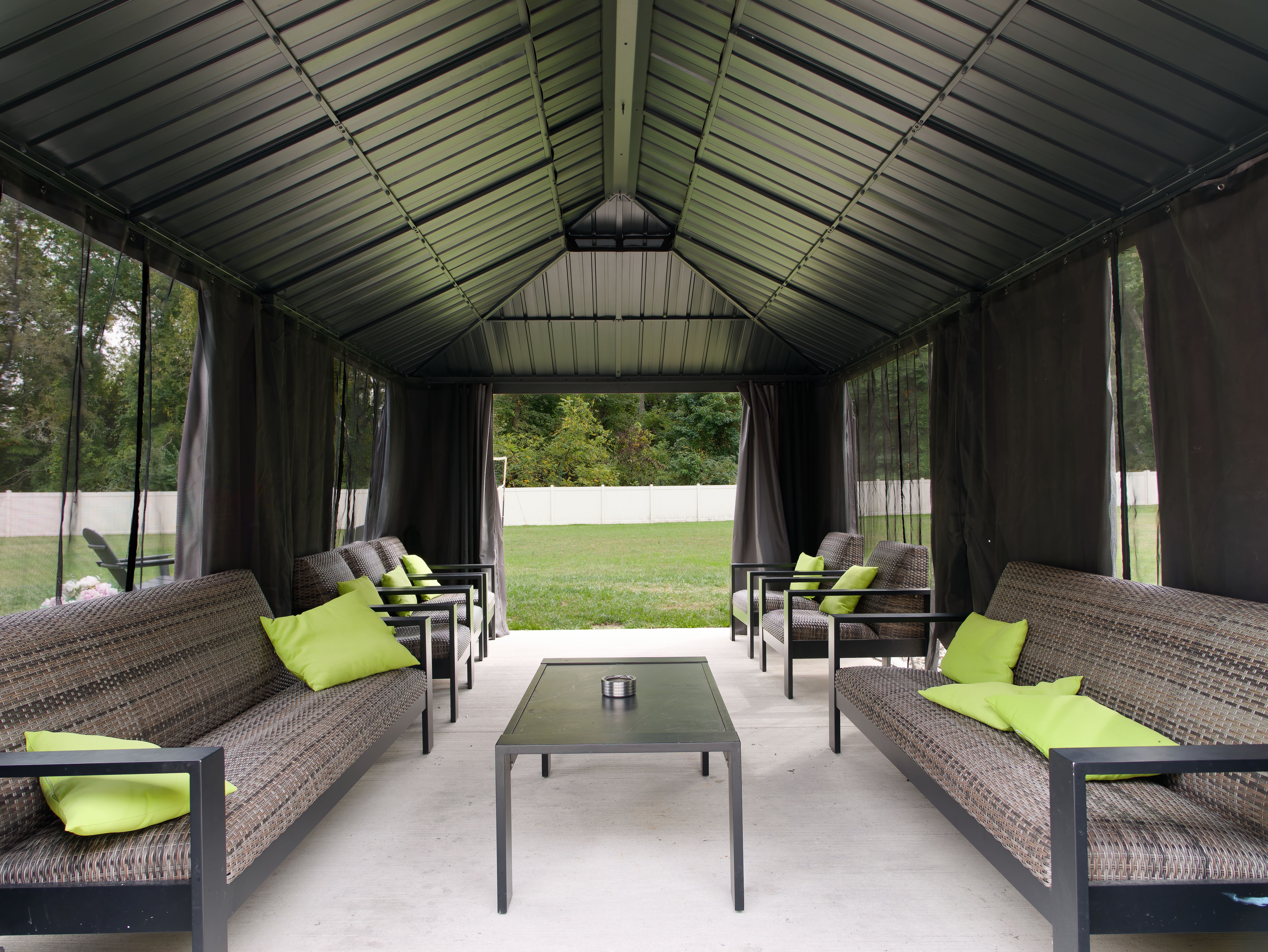 Covered outdoor seating area with sofas and green pillows.