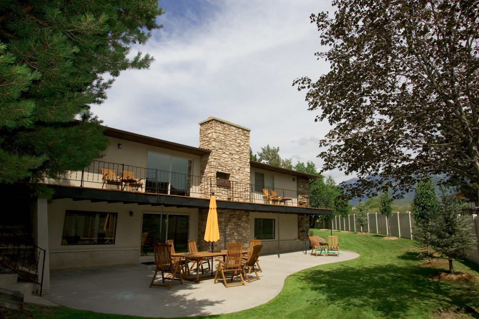 Two-story residence with patio seating and landscaped lawn