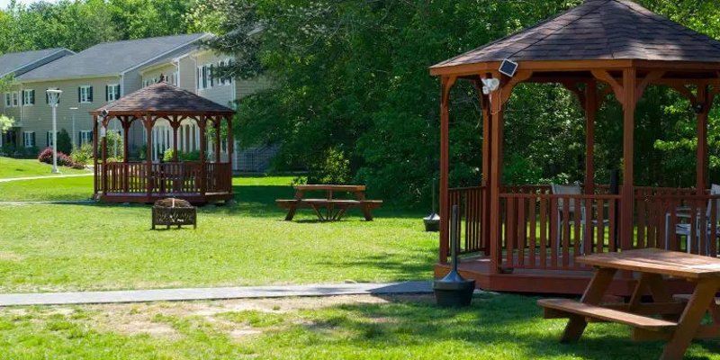 Peaceful outdoor area with charming wooden gazebos, picnic tables, and lush greenery, perfect for relaxation and social gatherings.