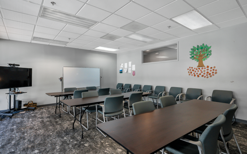 Group therapy room with tables, chairs, and display