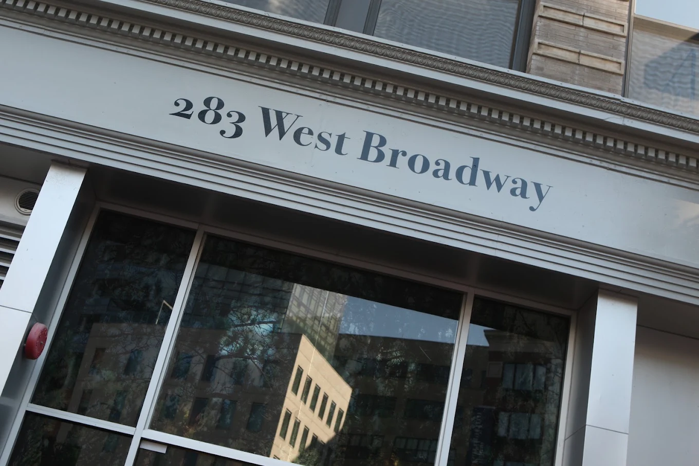 Building entrance at 283 West Broadway with large windows and street address signage