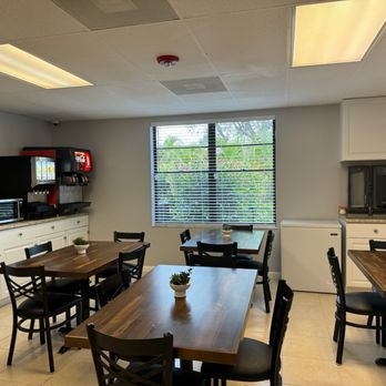 Dining area with wooden tables, chairs, and a snack station.