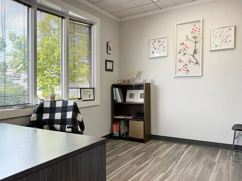 Small treatment room with desk, chairs, and sanitizer