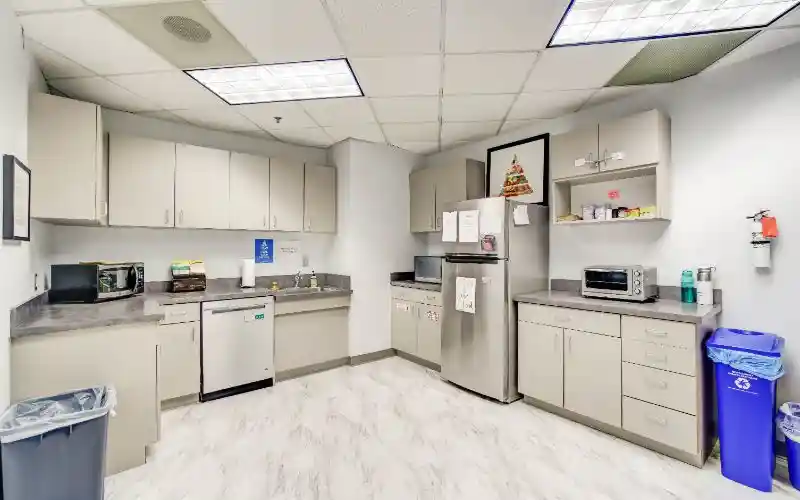Breakroom kitchen with fridge, cabinets, and countertop appliances